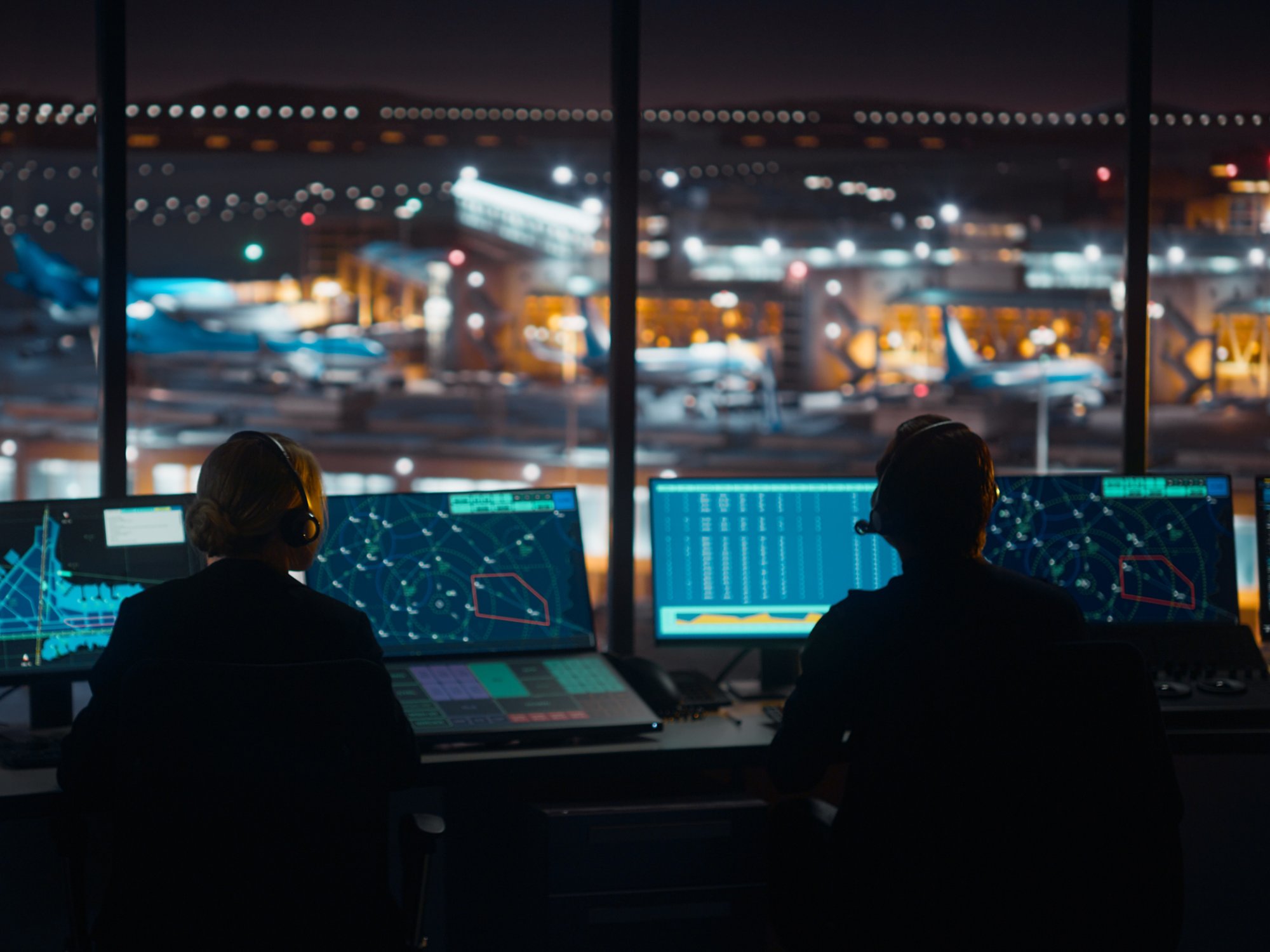 Diverse Air Traffic Control Team Working in a Modern Airport Tower at Night. Office Room is Full of Desktop Computer Displays with Navigation Screens, Airplane Flight Radar Data for Controllers.