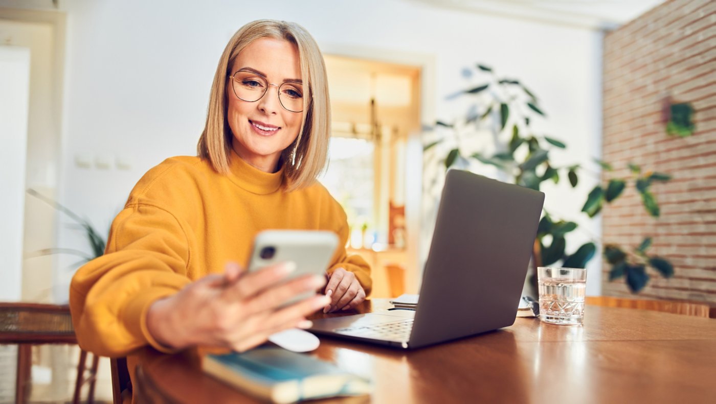 Woman orange sweater working on laptop and smartphone 16x9