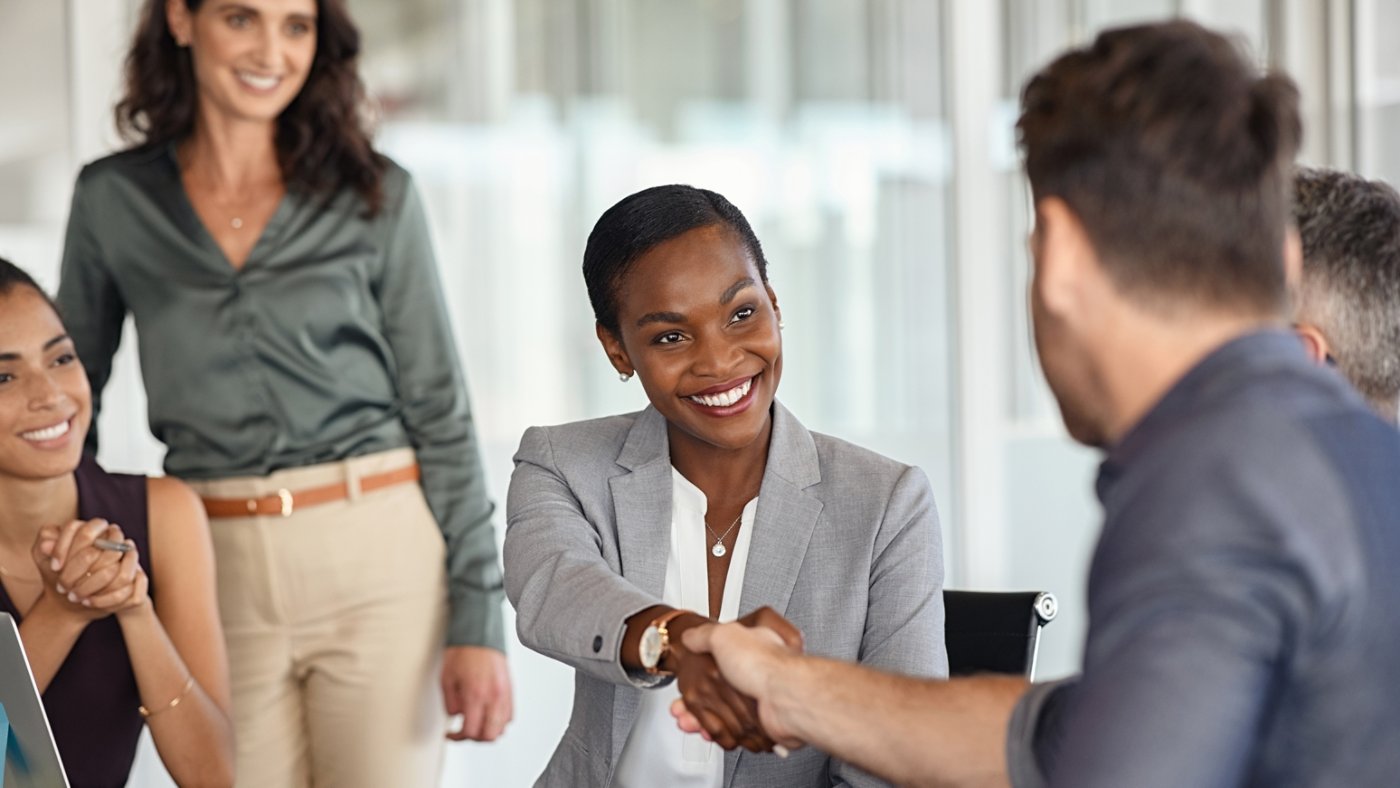 Happy black businesswoman and businessman shaking hands at meeting. Professional business executive leaders making handshake agreement. Happy business man closing deal at negotiations with african american woman.