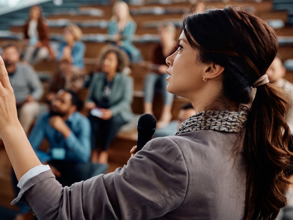 Businesswoman speaking to group of entrepreneurs during an education event at convention center.