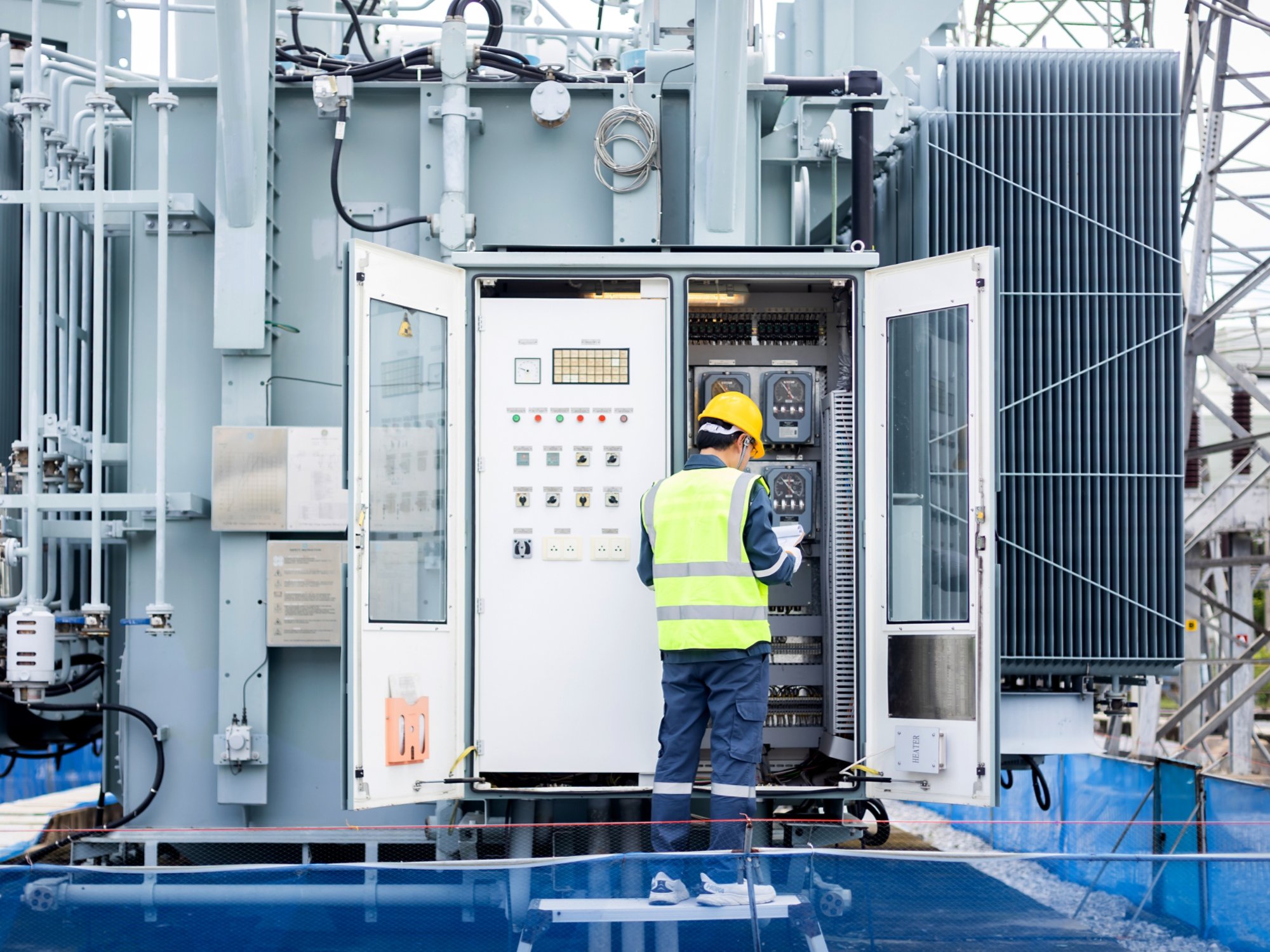 An engineer is working on high voltage power substation performing inspection and check to ensure infrastructure operates safely and efficiently in this industrial environment
