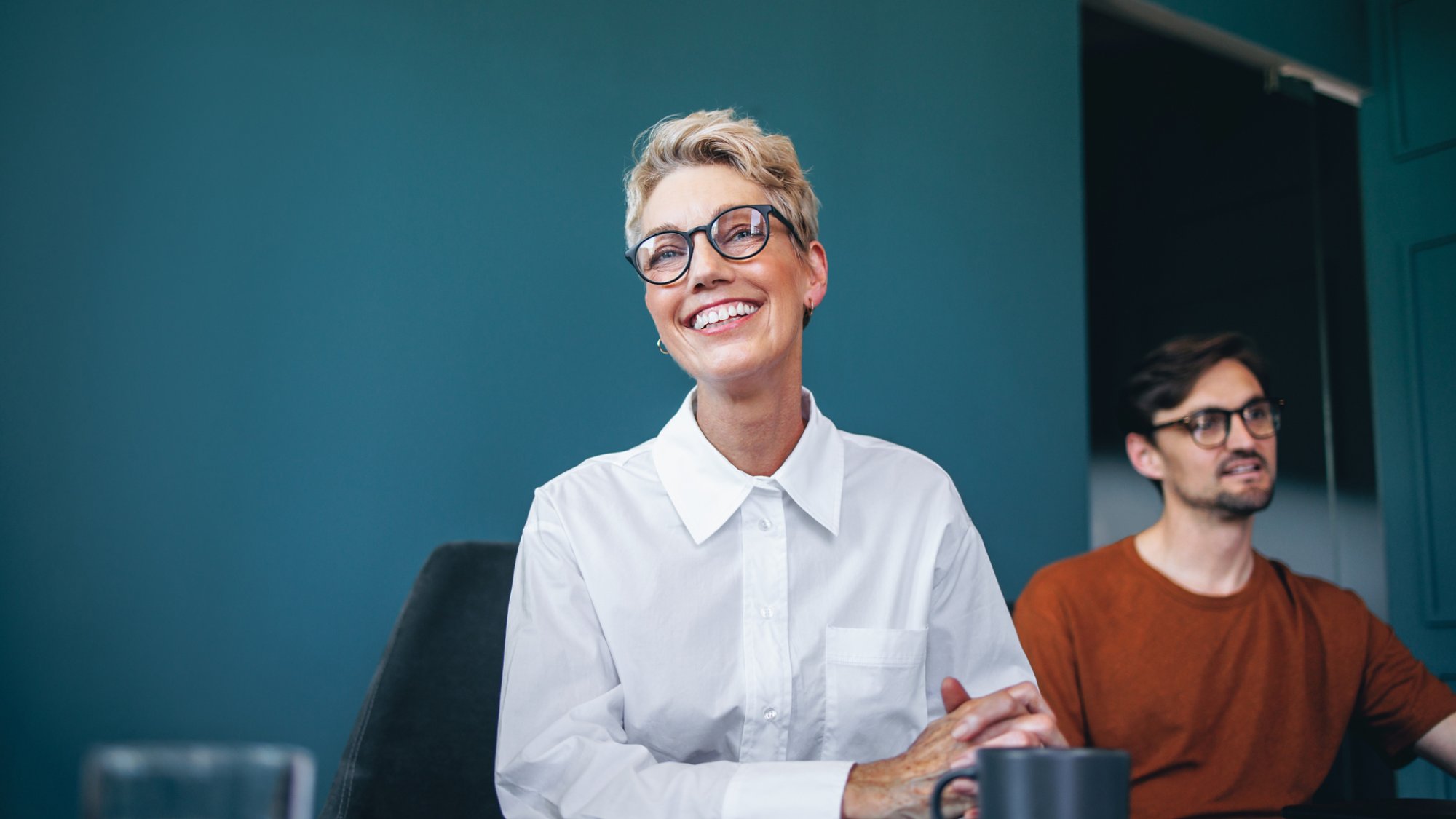 Successful business professional engaging with her team and participating in a collaboration. Accomplished female entrepreneur smiling while sitting with her colleagues in a boardroom meeting.