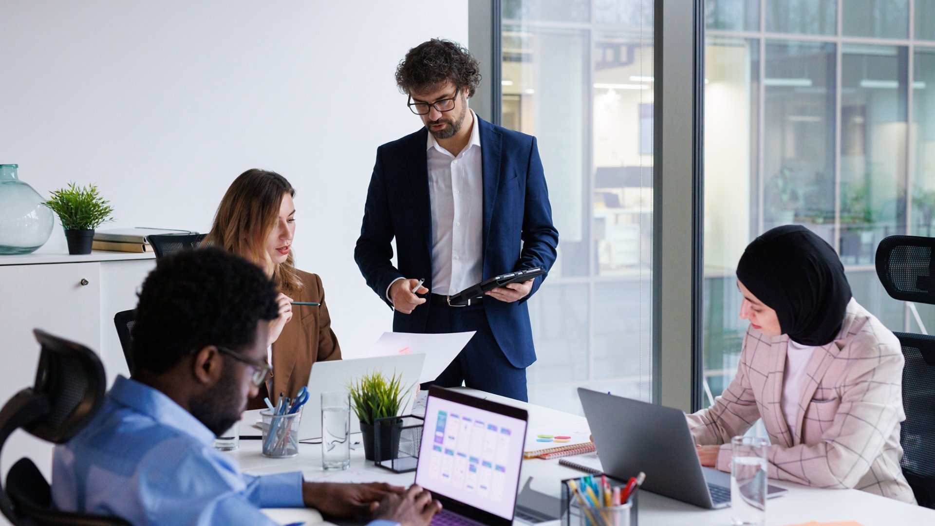 Manager with tablet in hands conducting staff meeting at office