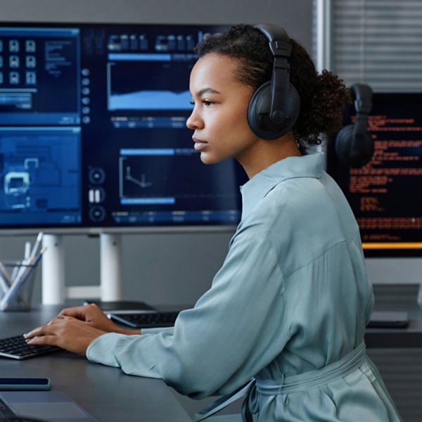 Young computer programmer wearing wireless headphones working on desktop PC