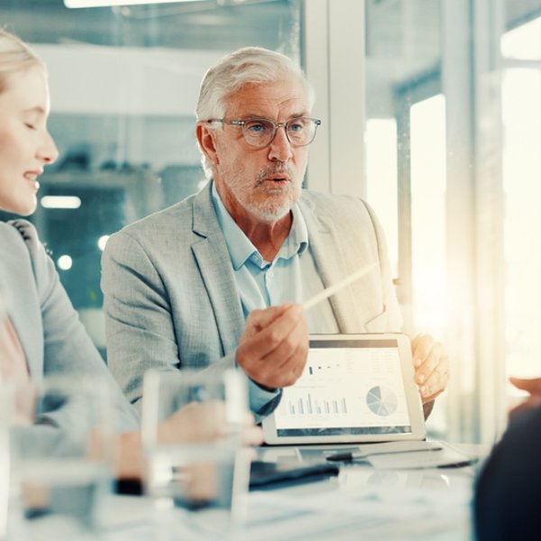 Presentation, businessman and tablet screen with charts in meeting, investment metrics or planning. Office, team or brainstorming with financial dashboard, data or performance analysis with kpi stats.