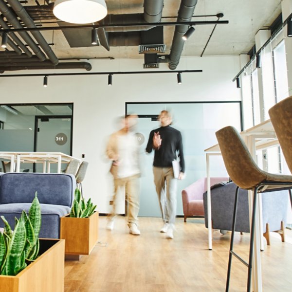motion blur of business partners walking in lounge of contemporary coworking environment with high tech interior, modern furniture and natural plants, dynamic business and productivity concept