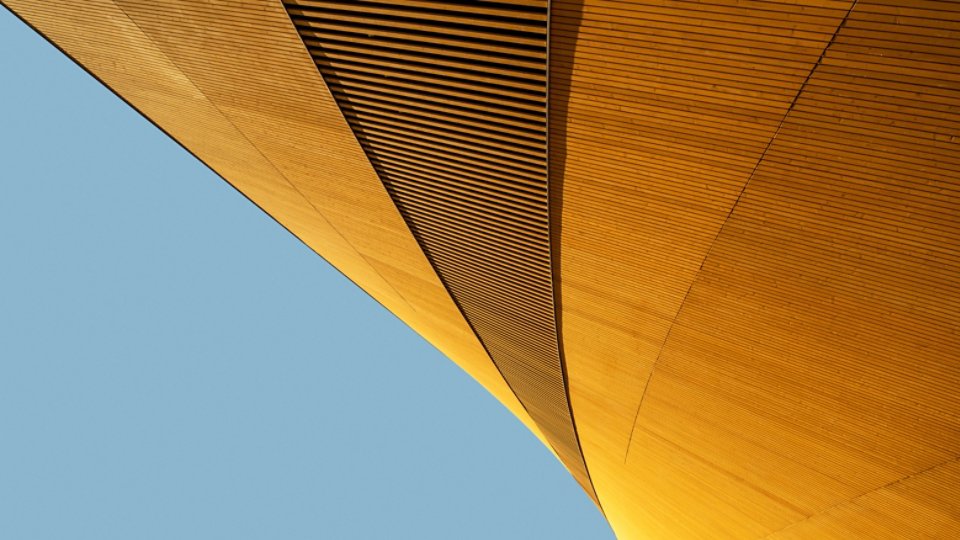 Abstract shape of modern wooden building against blue background, elegant minimalist geometric architecture