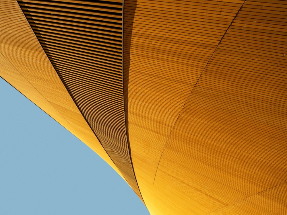 Abstract shape of modern wooden building against blue background, elegant minimalist geometric architecture