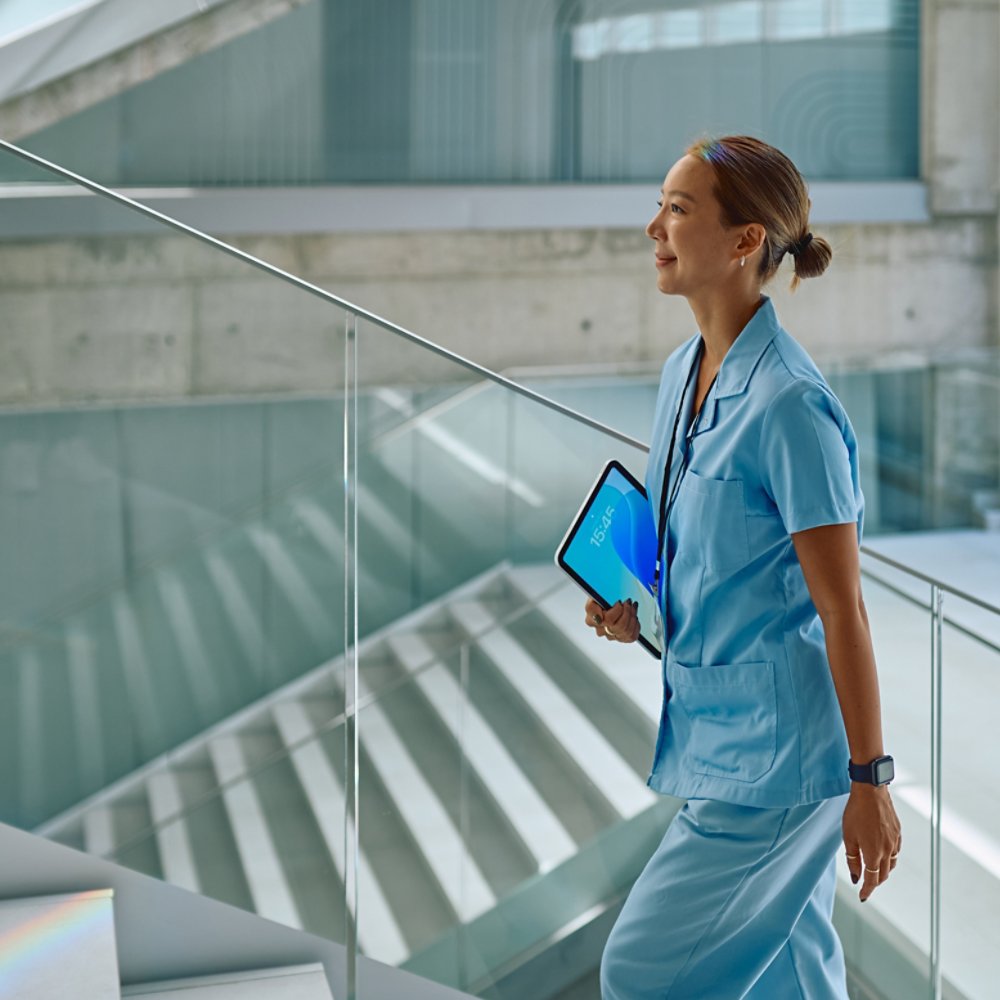 Confident doctor walking up stairs in modern hospital holding tablet