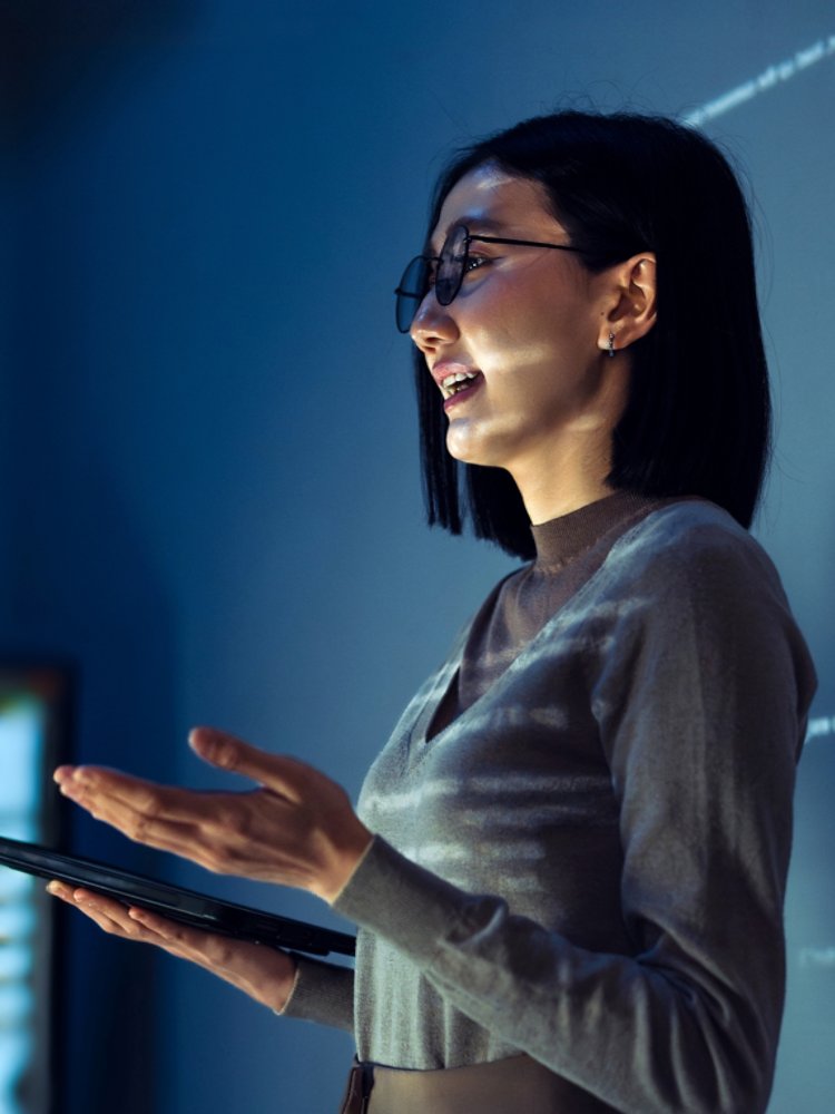 asian woman programmer standing in front of a screen with code projected  presentation the integration of technology and human expertise in software development