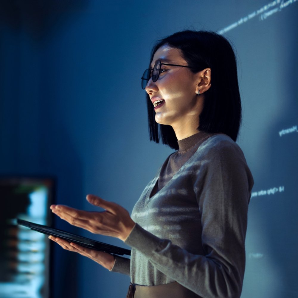 asian woman programmer standing in front of a screen with code projected  presentation the integration of technology and human expertise in software development
