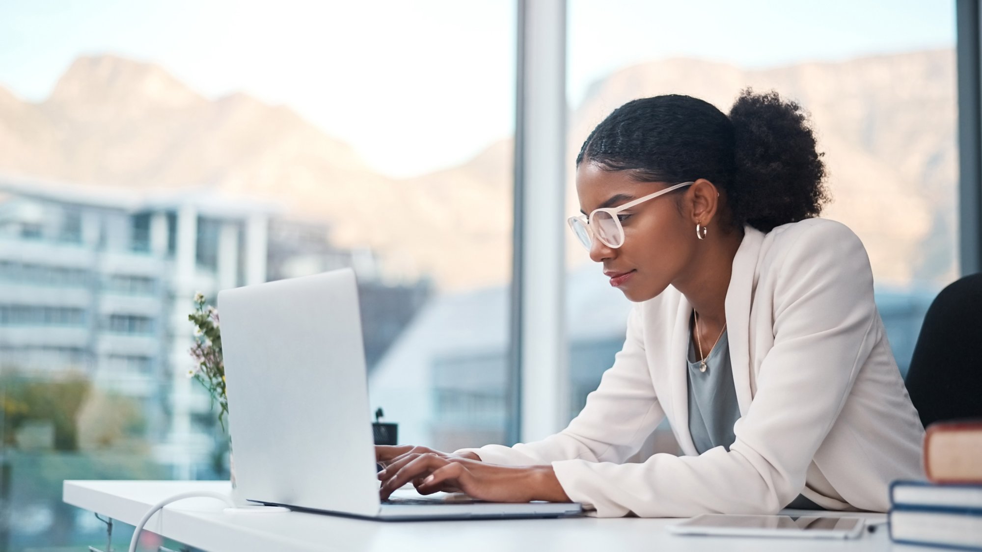 Data professional and secretary typing an email on a laptop and doing online research while working in an office. African entrepreneur looking focused while using the internet for work.