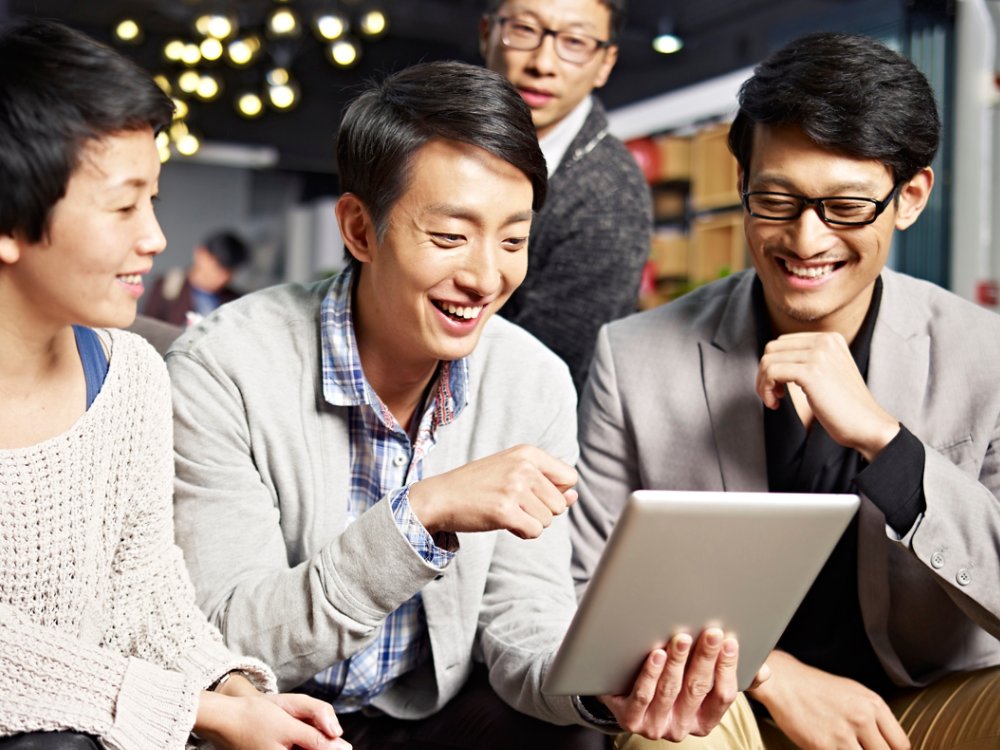 young asian businesspeople sitting in sofa looking at tablet computer, happy and smiling.