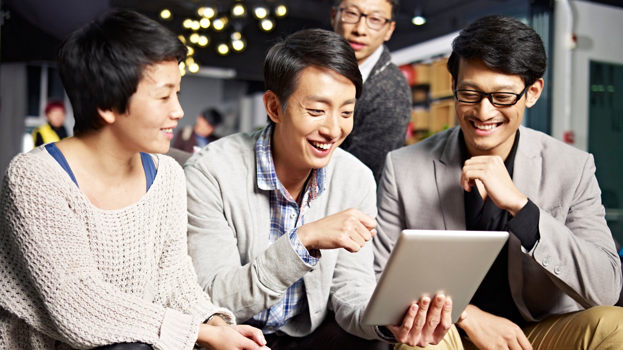 young asian businesspeople sitting in sofa looking at tablet computer, happy and smiling.
