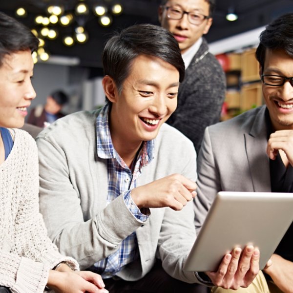 young asian businesspeople sitting in sofa looking at tablet computer, happy and smiling.