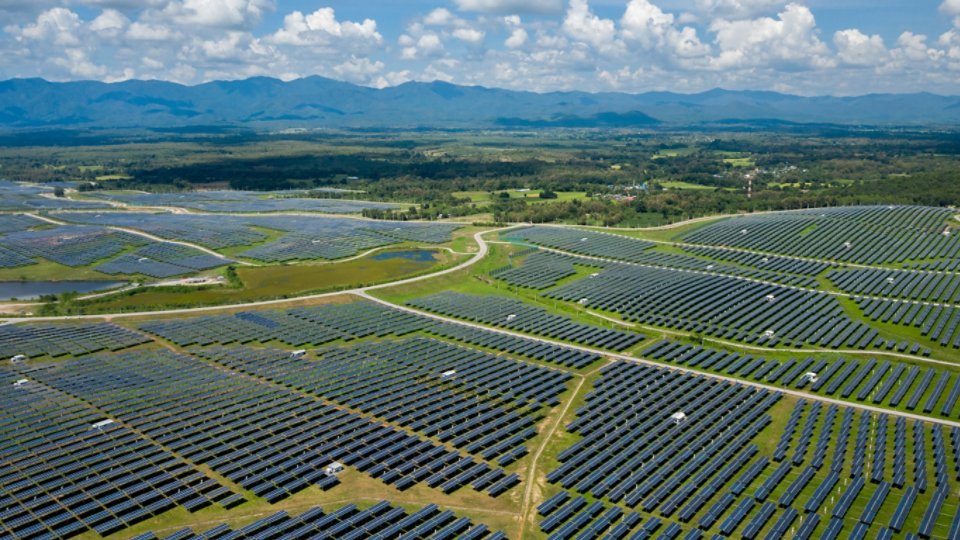 Aerial view of many solar energy modules or panels rows pattern over the green landscape