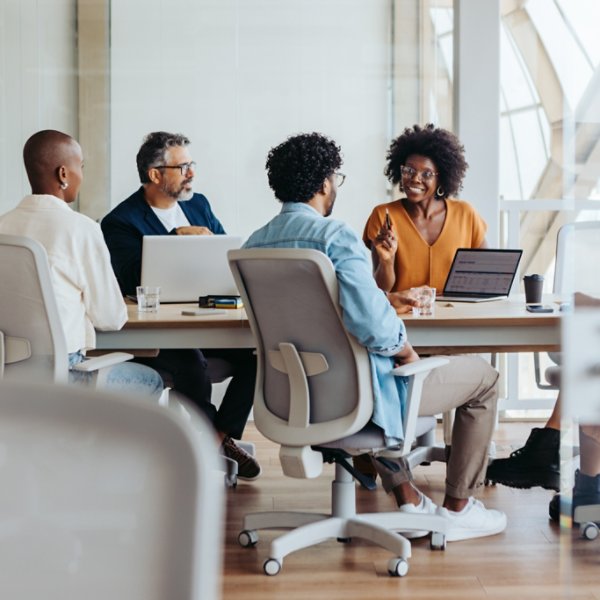 Group of business people engaged in a lively discussion and brainstorming session. They work collaboratively, sharing ideas and smiling with enthusiasm. This dynamic team exemplifies successful teamwork in a modern, productive workplace.