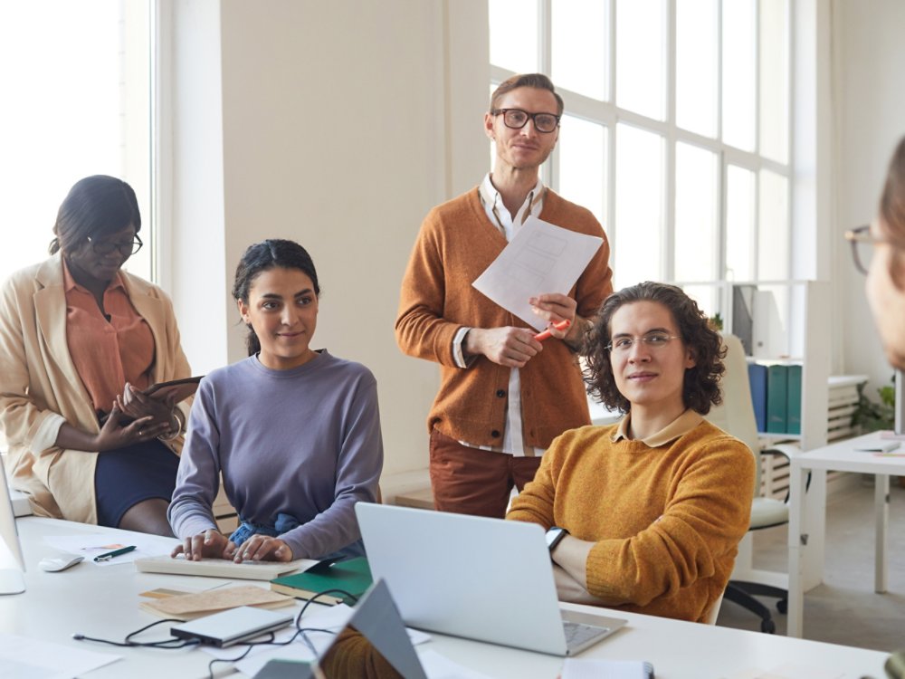 Portrait of diverse IT development team discussing project while working on software production in office