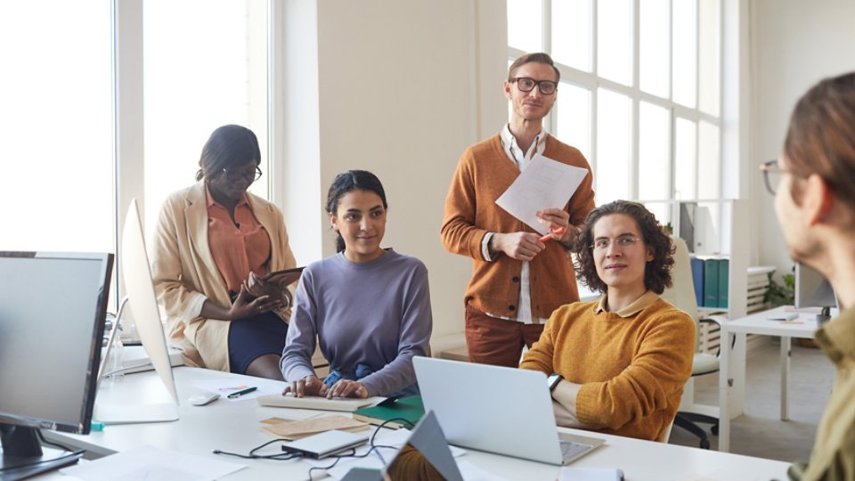 Portrait of diverse IT development team discussing project while working on software production in office