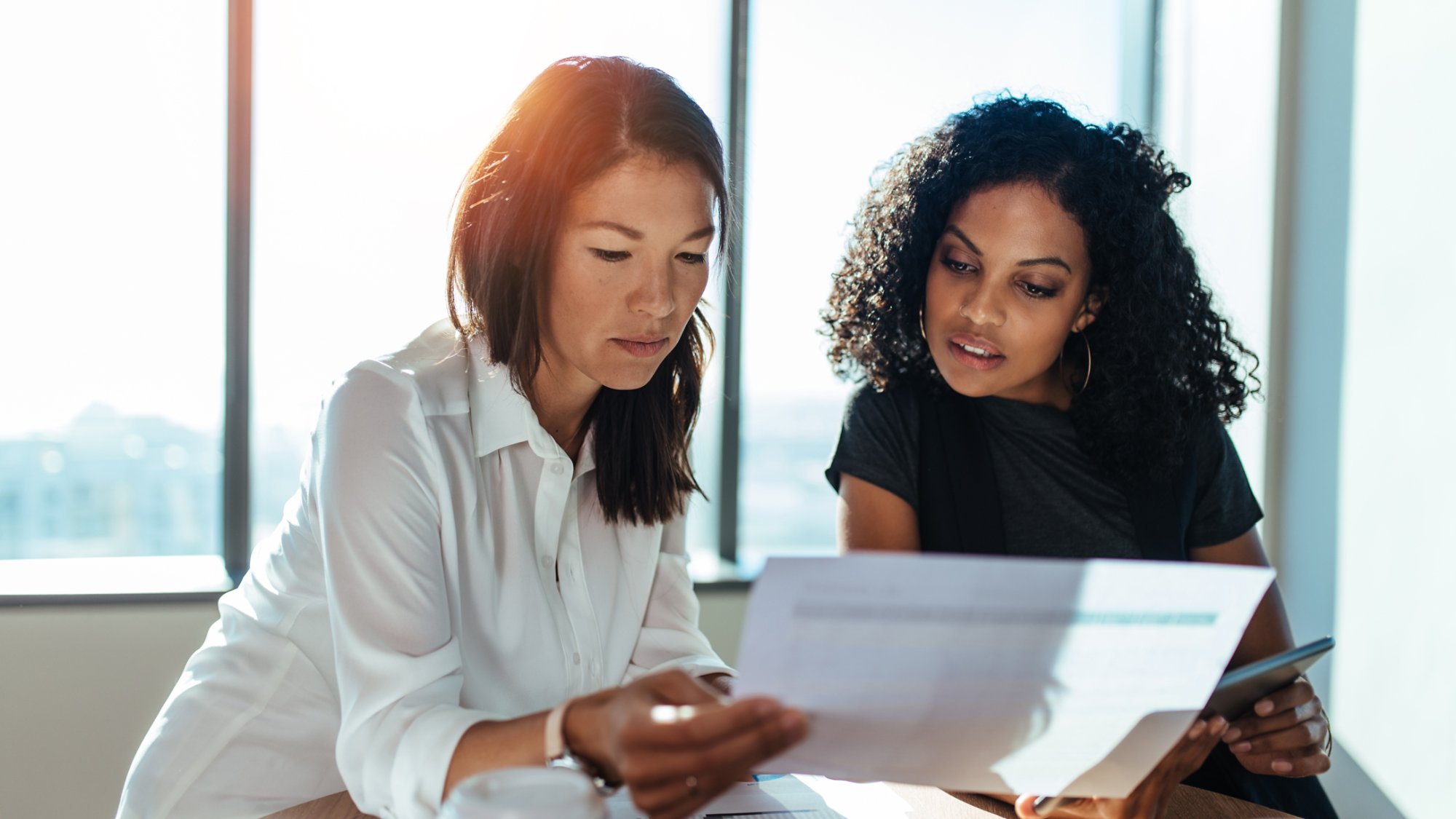 Businesswomen having a meeting sitting at table in office. Two young entrepreneurs discussing business matters.