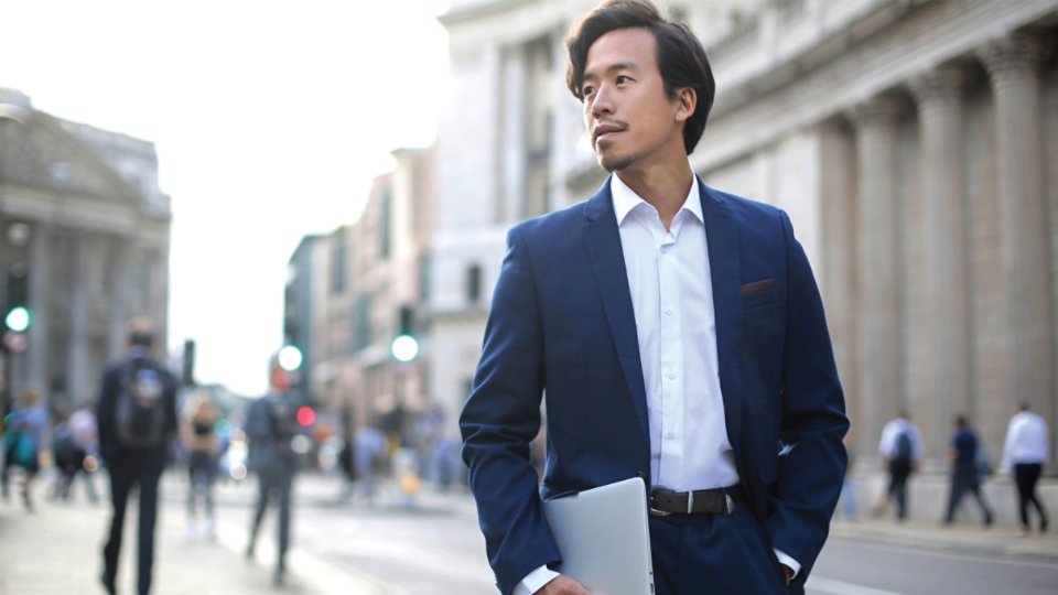 portrait of an Asian businessman walking down a street in the financial district carrying a folder