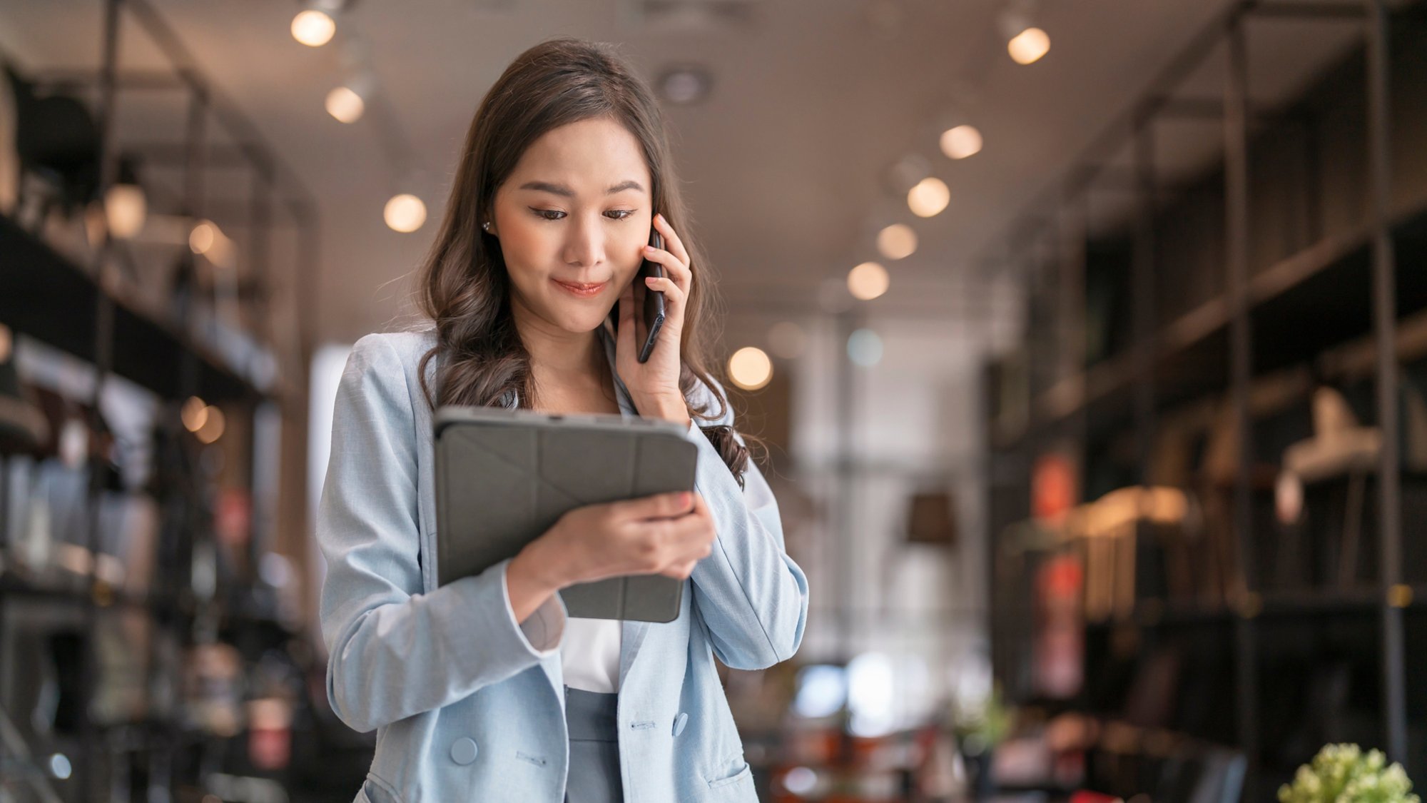 smart business owner asian female startup entrepreneur small business manager businesswoman wear smart casual cloth smile hand use tablet smartphone working inventory checking in showroom studio