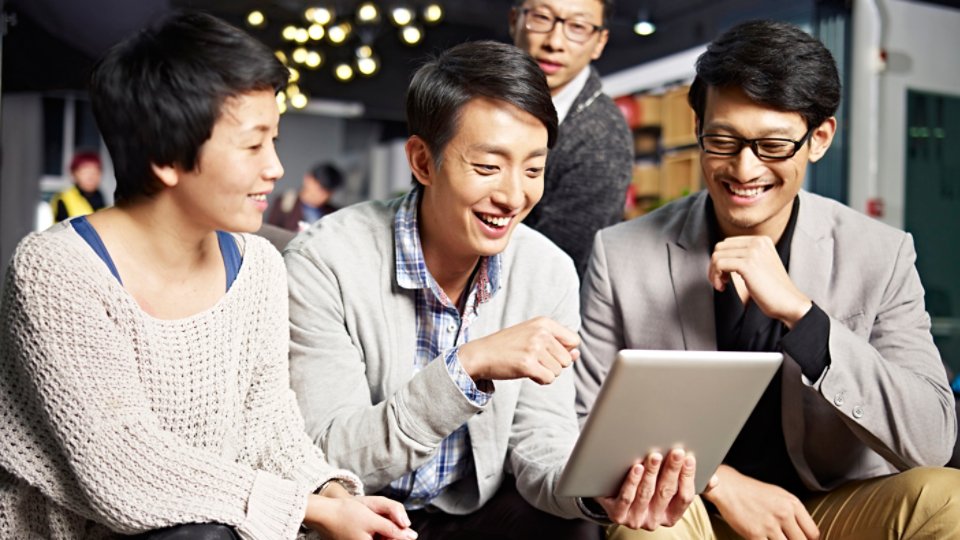 young asian businesspeople sitting in sofa looking at tablet computer, happy and smiling.