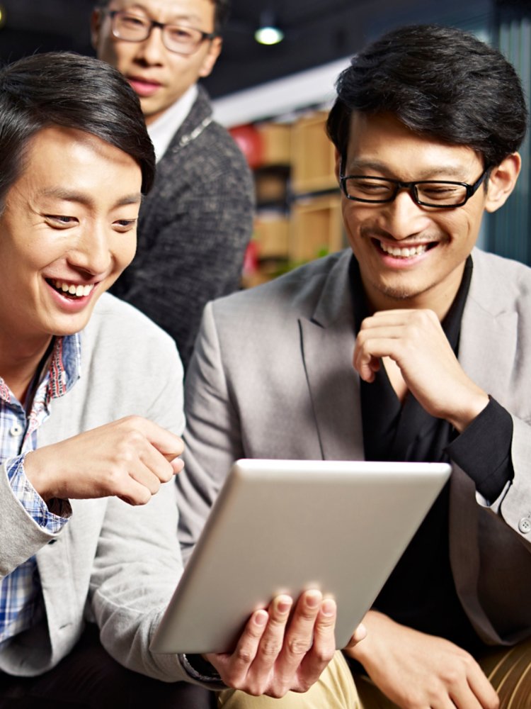 young asian businesspeople sitting in sofa looking at tablet computer, happy and smiling.