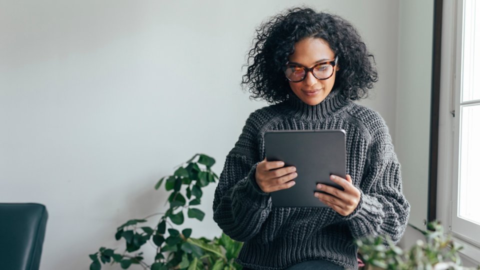 Young woman wearing glasses watching something on her digital tablet (copy space).