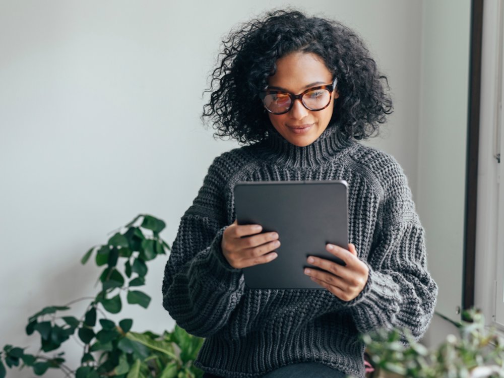 Young woman wearing glasses watching something on her digital tablet (copy space).