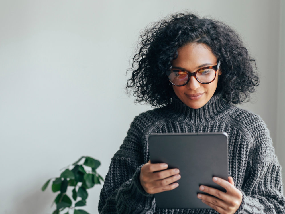 Young woman wearing glasses watching something on her digital tablet (copy space).