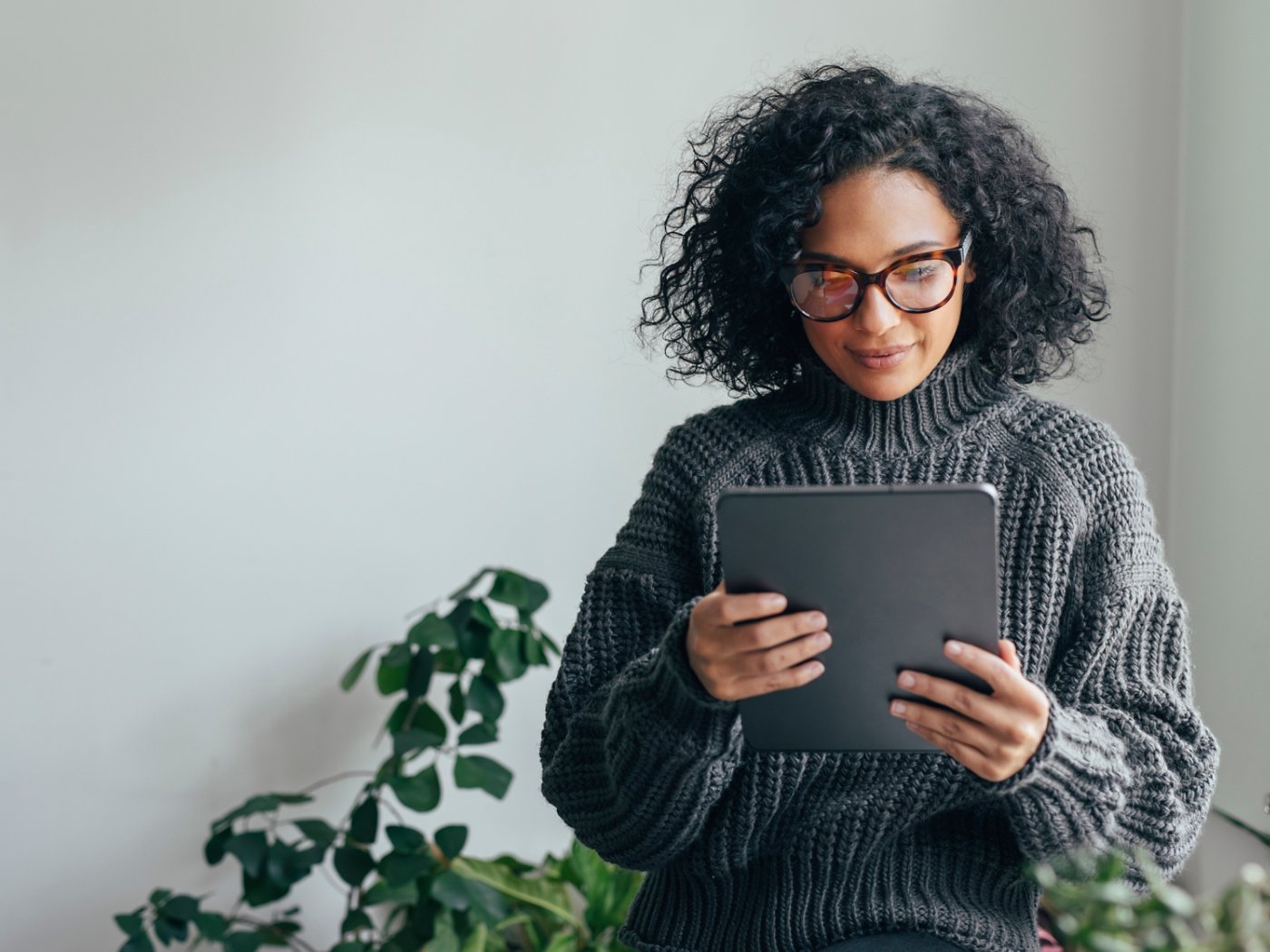 Young woman wearing glasses watching something on her digital tablet (copy space).