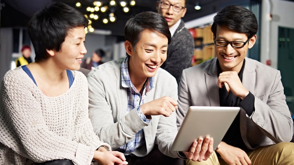 young asian businesspeople sitting in sofa looking at tablet computer, happy and smiling.