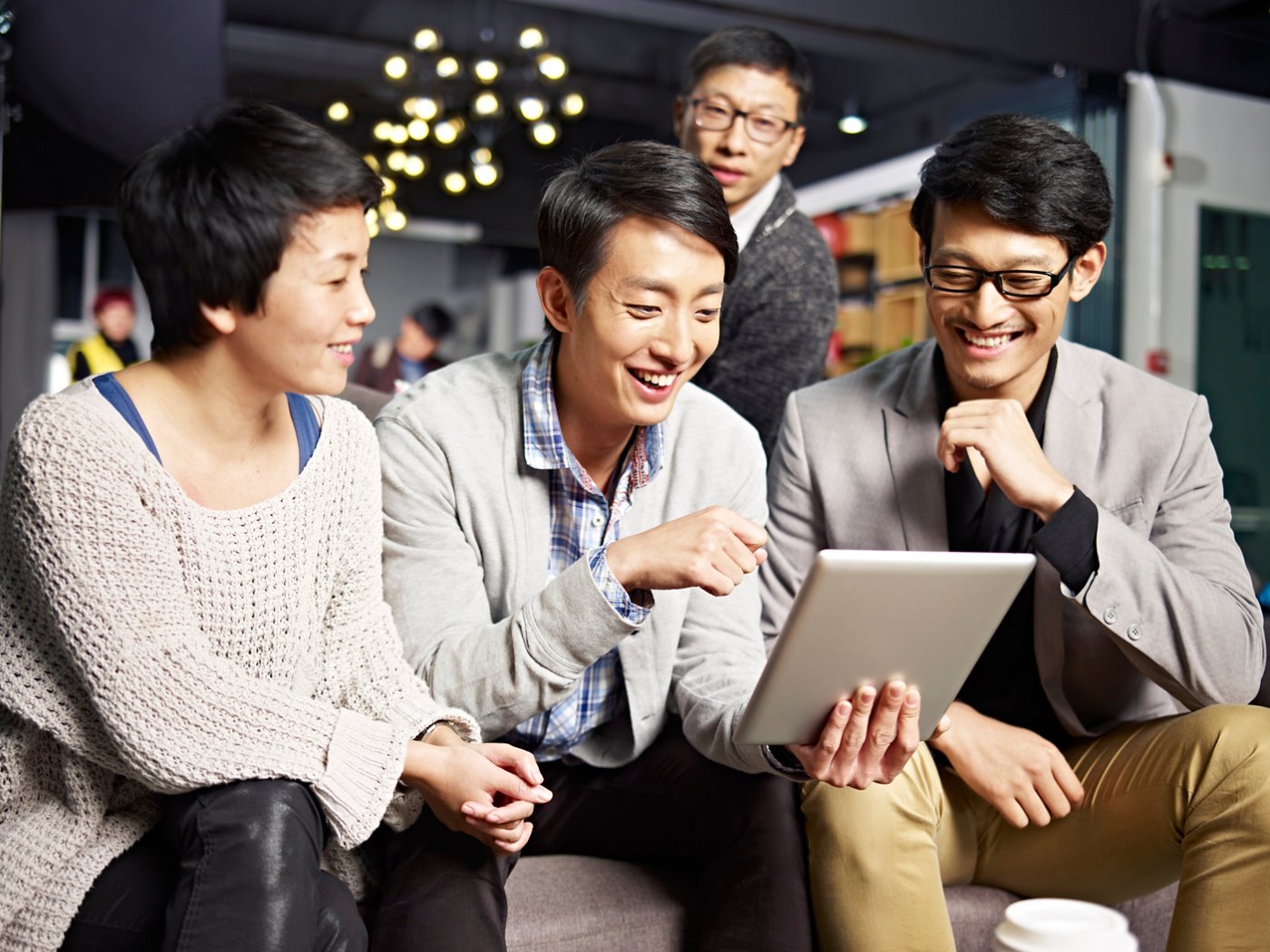 young asian businesspeople sitting in sofa looking at tablet computer, happy and smiling.