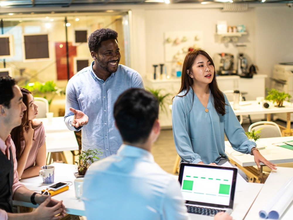 Group of young, modern people sitting on business meeting in modern coworking space and suggesting ideas for the best business strategy