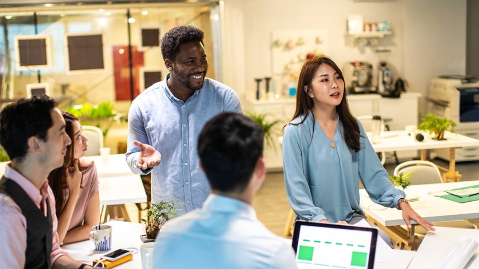 Group of young, modern people sitting on business meeting in modern coworking space and suggesting ideas for the best business strategy