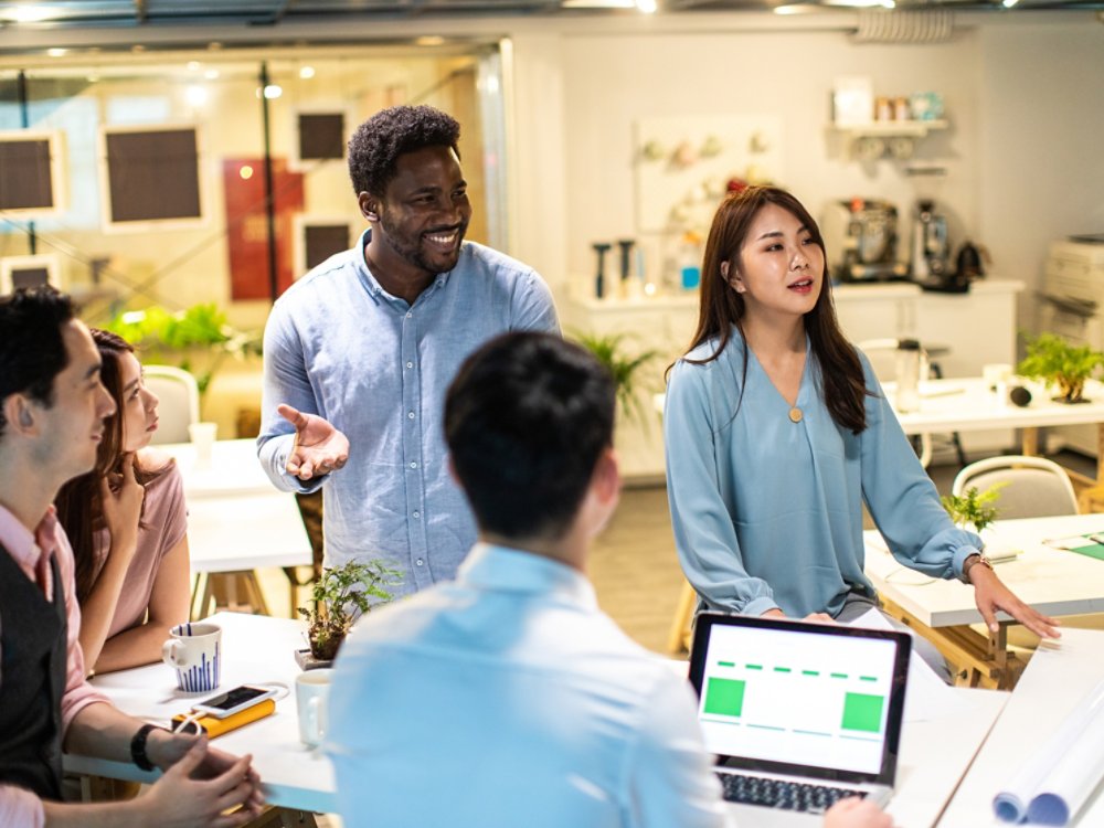 Group of young, modern people sitting on business meeting in modern coworking space and suggesting ideas for the best business strategy