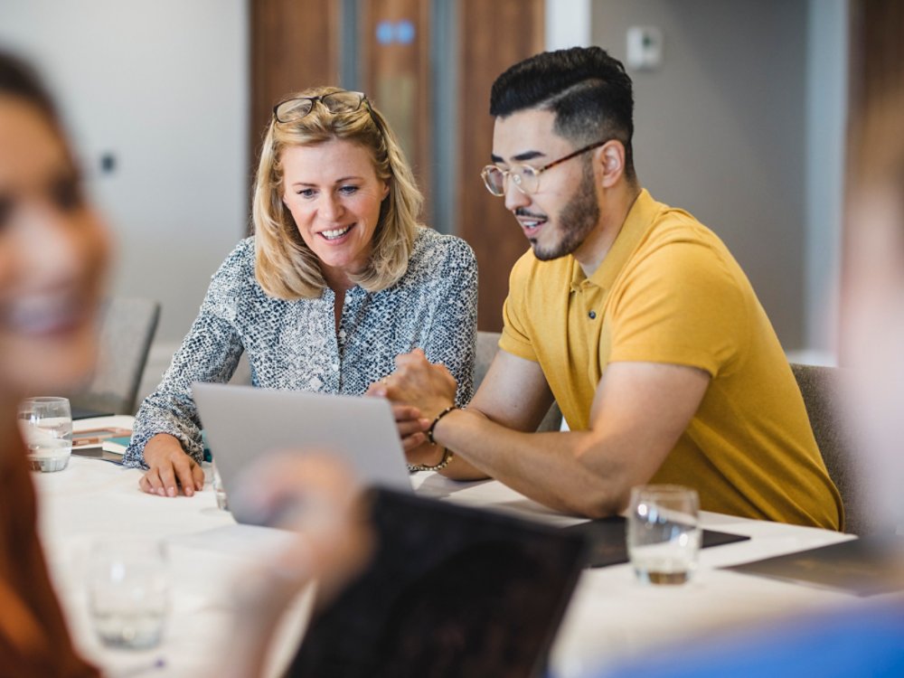 Mature businesswoman smiling with employee, working together, collaboration, teamwork