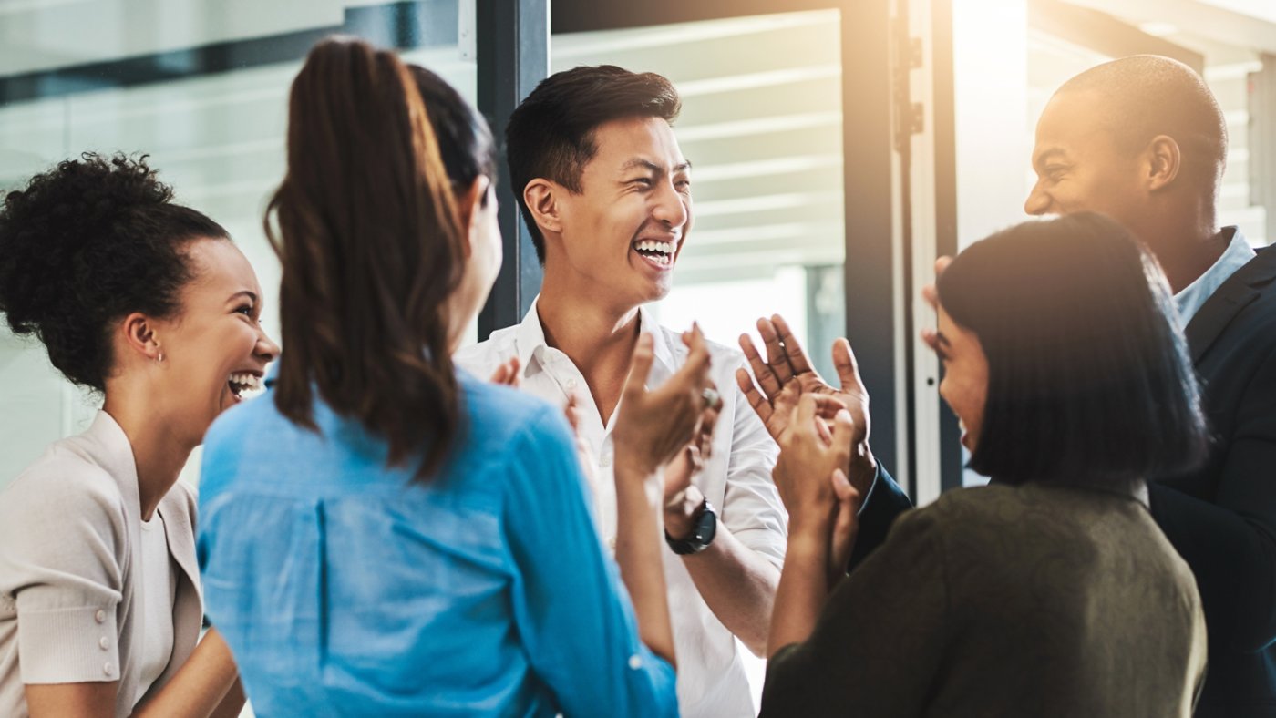 Shot of a group of young businesspeople standing together and clapping in a modern office