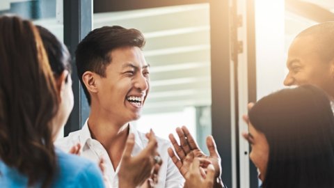 Shot of a group of young businesspeople standing together and clapping in a modern office
