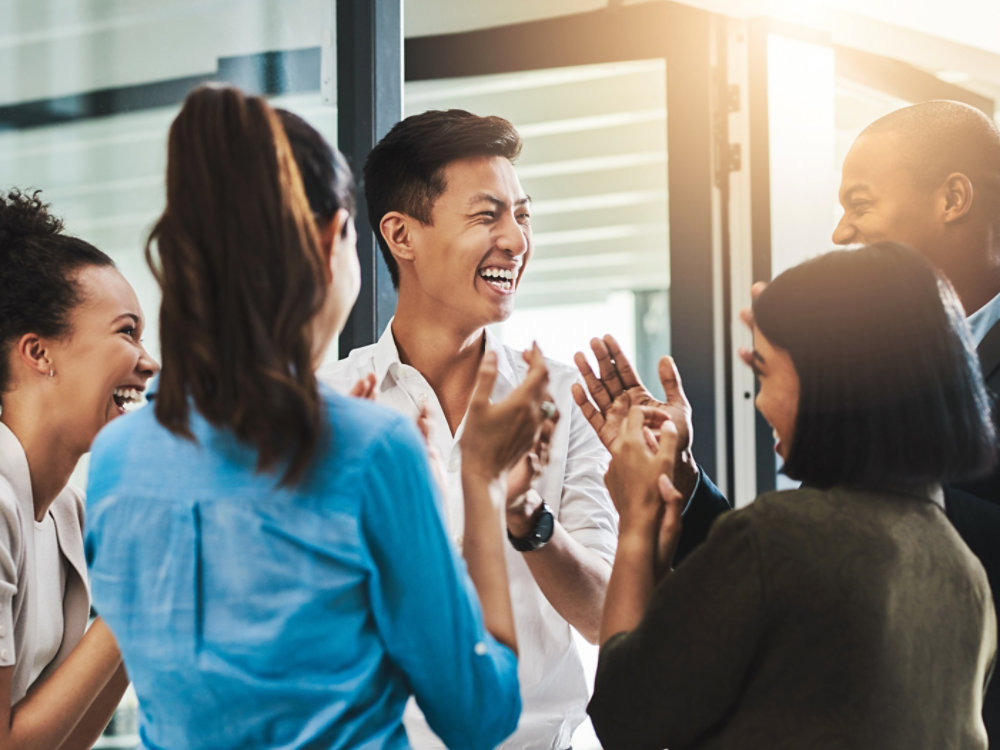 Shot of a group of young businesspeople standing together and clapping in a modern office