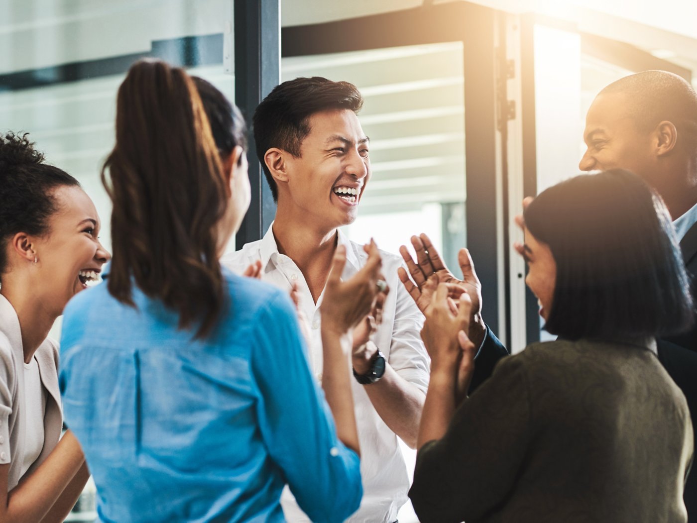 Shot of a group of young businesspeople standing together and clapping in a modern office