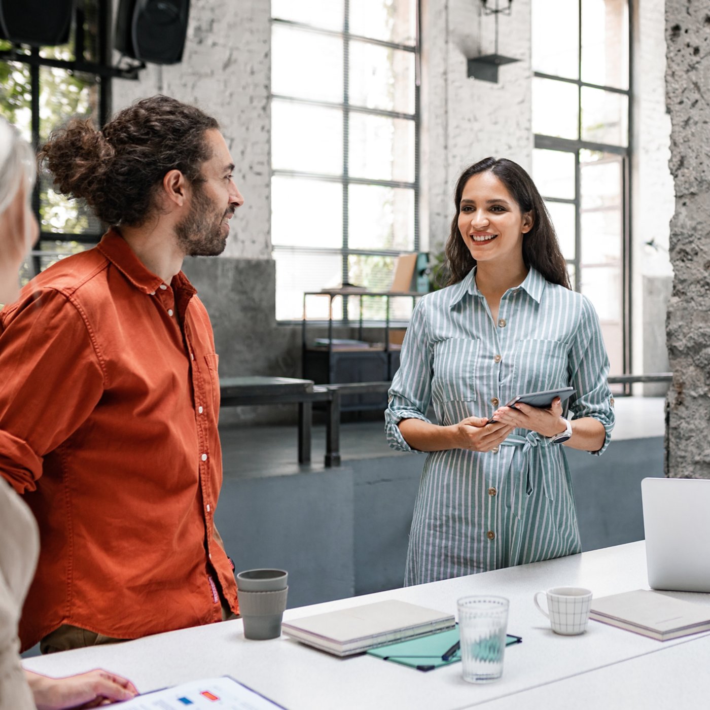 Group of successful businesspeople cooperating by participating in a casual meeting around a standing desk.