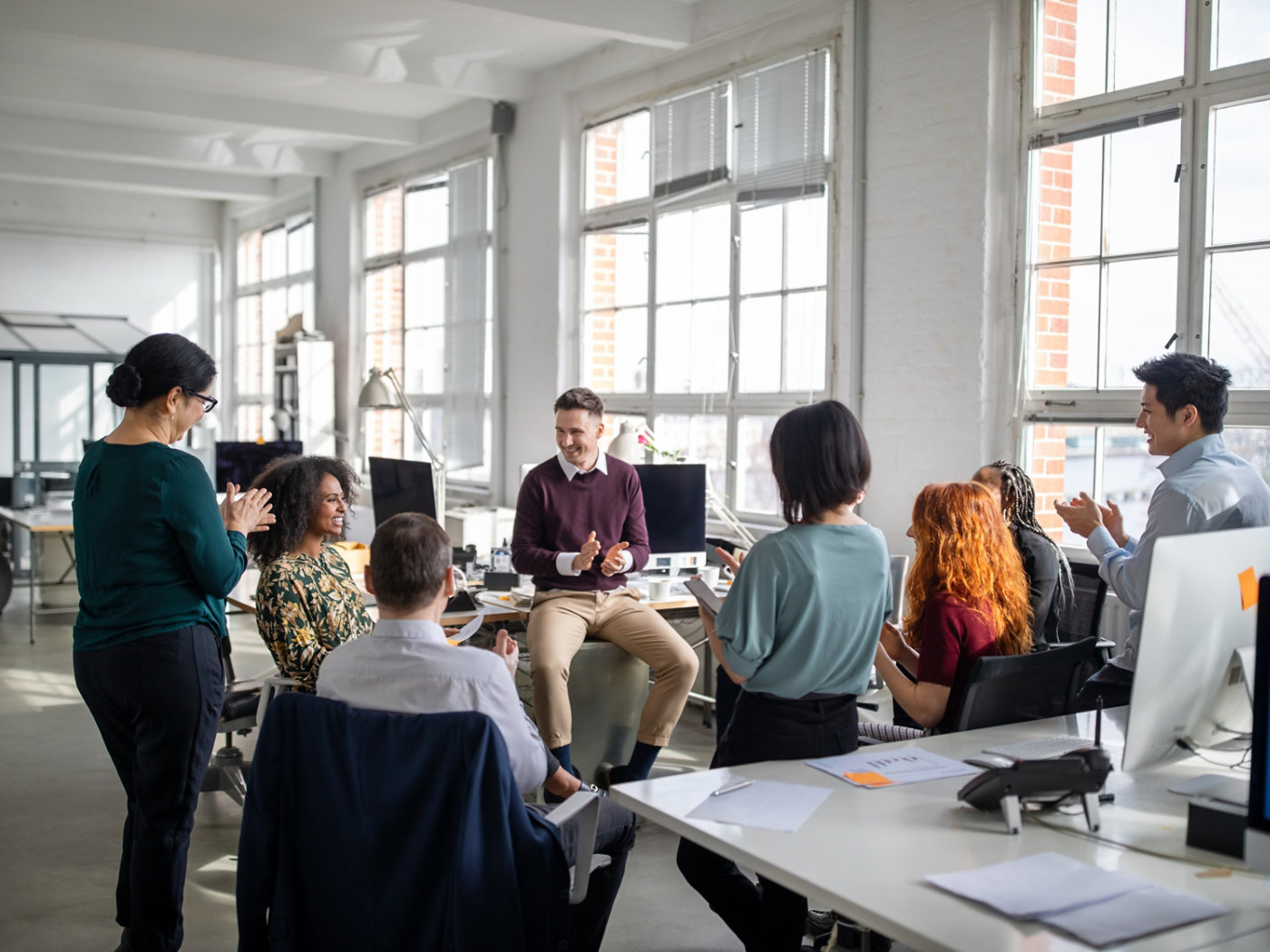 Group of business people clapping hands for a coworker in staff meeting. Multi-ethnic business team applauding for a female colleague in a meeting.