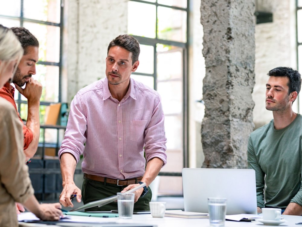 Group of businesspeople cooperating by participating in a casual meeting around a standing desk.