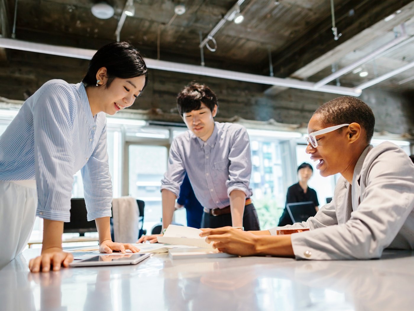 A group of multi-ethnic young business people are talking to each other in a modern working space in Tokyo.