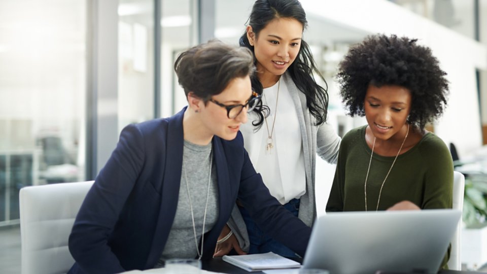 Shot of a group of businesswomen using a laptop during a meeting at work