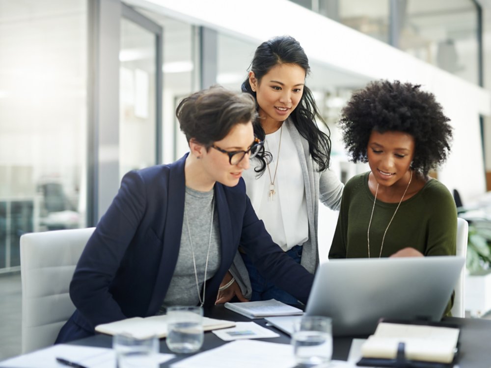 Shot of a group of businesswomen using a laptop during a meeting at work