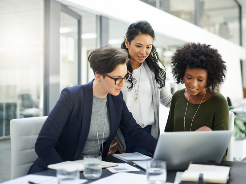 Shot of a group of businesswomen using a laptop during a meeting at work