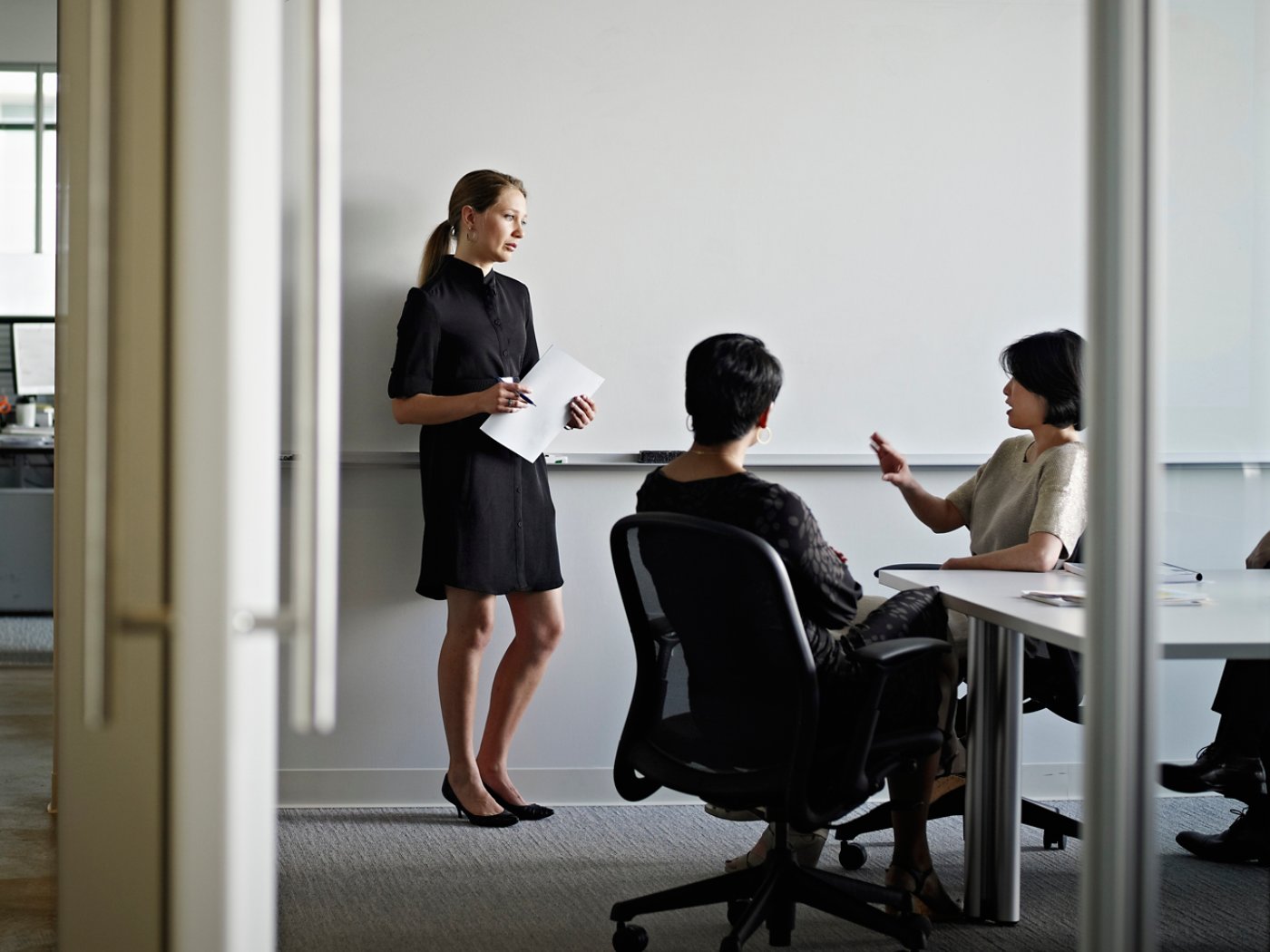 Businesswoman standing in conference room in discussion with coworkers